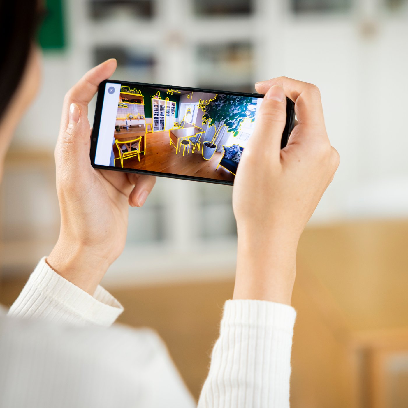 Una persona guarda il cellulare su cui si vede un progetto creato con un tool IKEA.