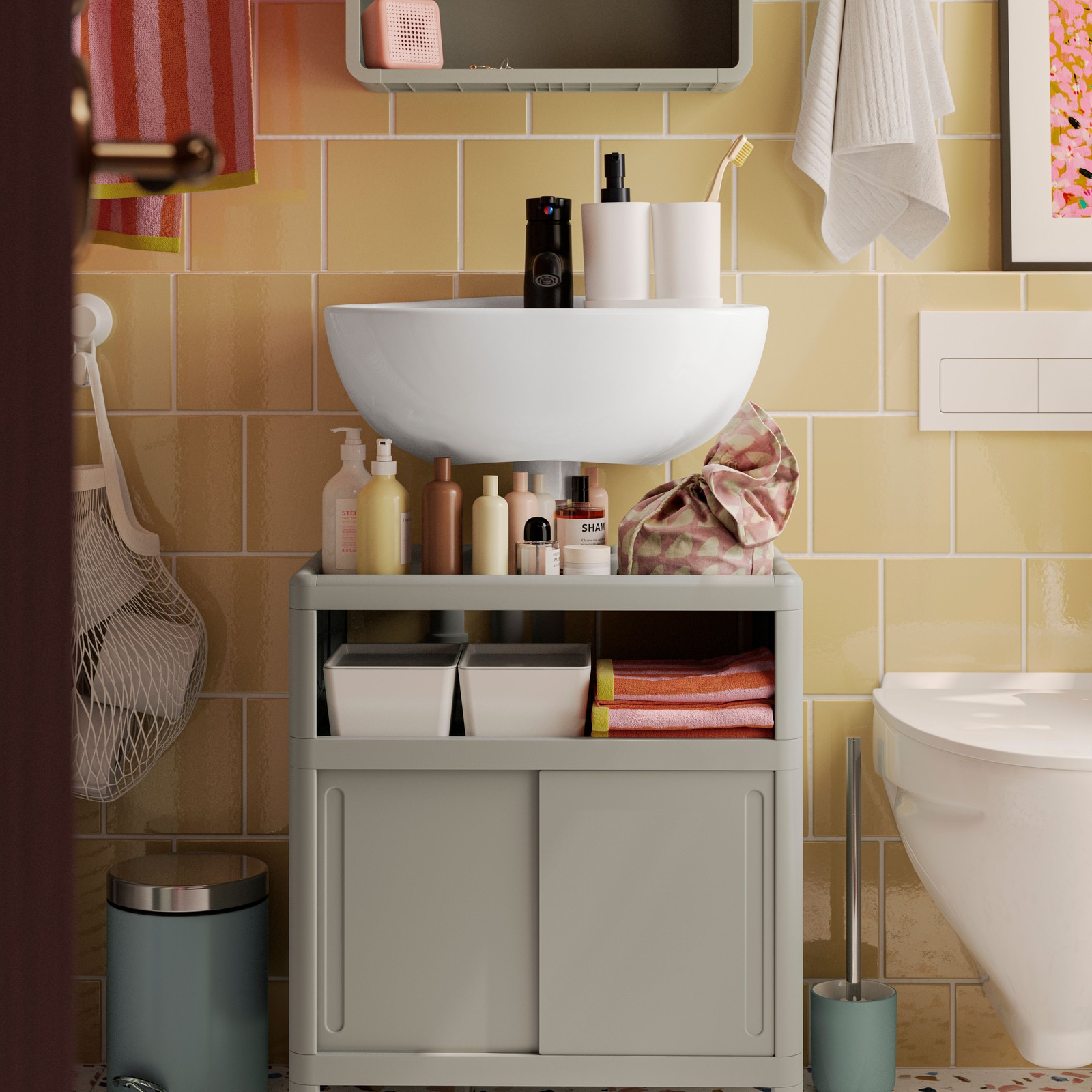 An IVÖSJÖN wash-basin base cabinet in green and a SKATSJÖN single wash-basin are in a bathroom with yellow-tiled walls.
