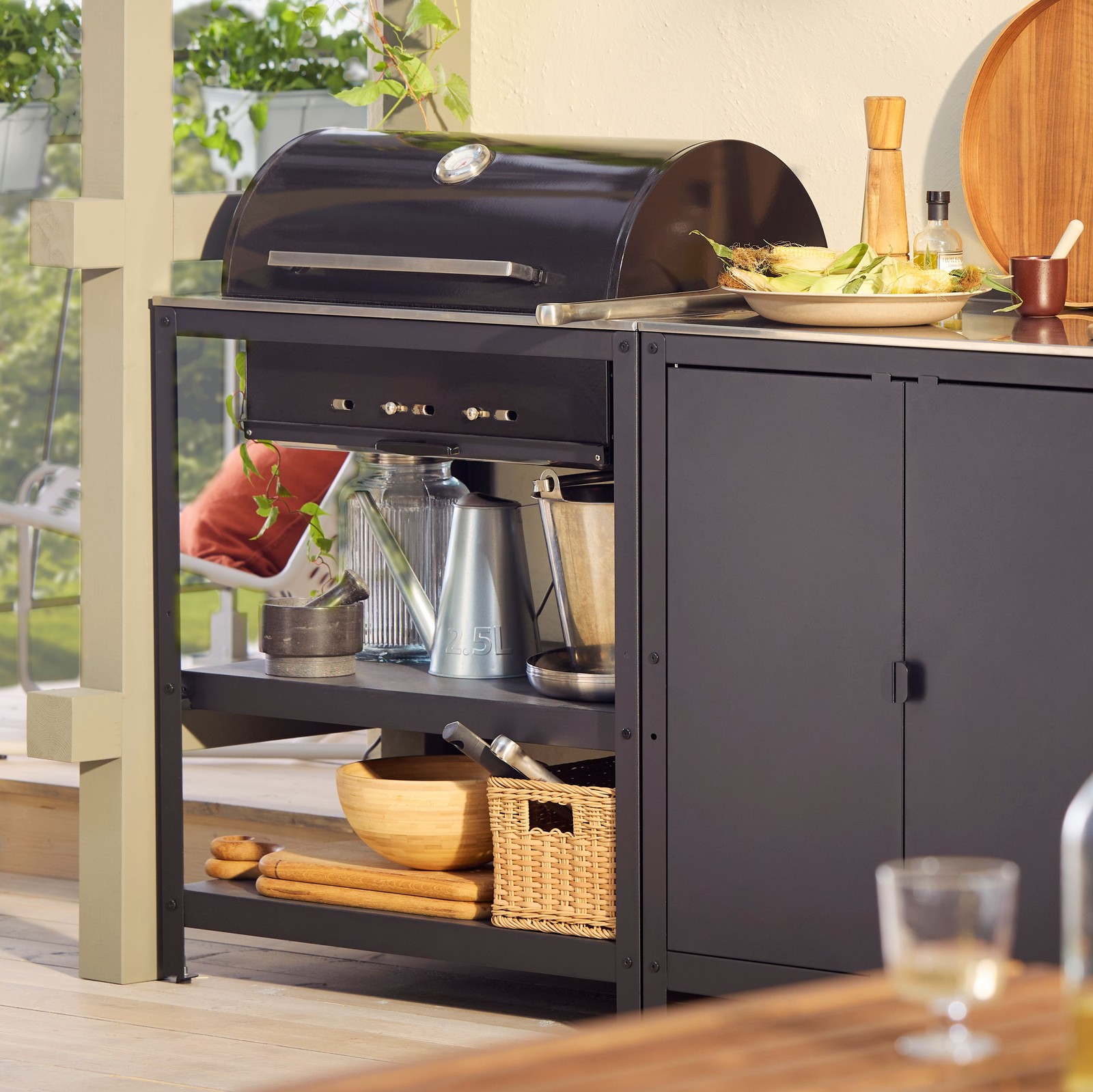 A GRILLSKÄR outdoor charcoal barbeque and kitchen island in black stainless steel with grilling and cooking accessories.