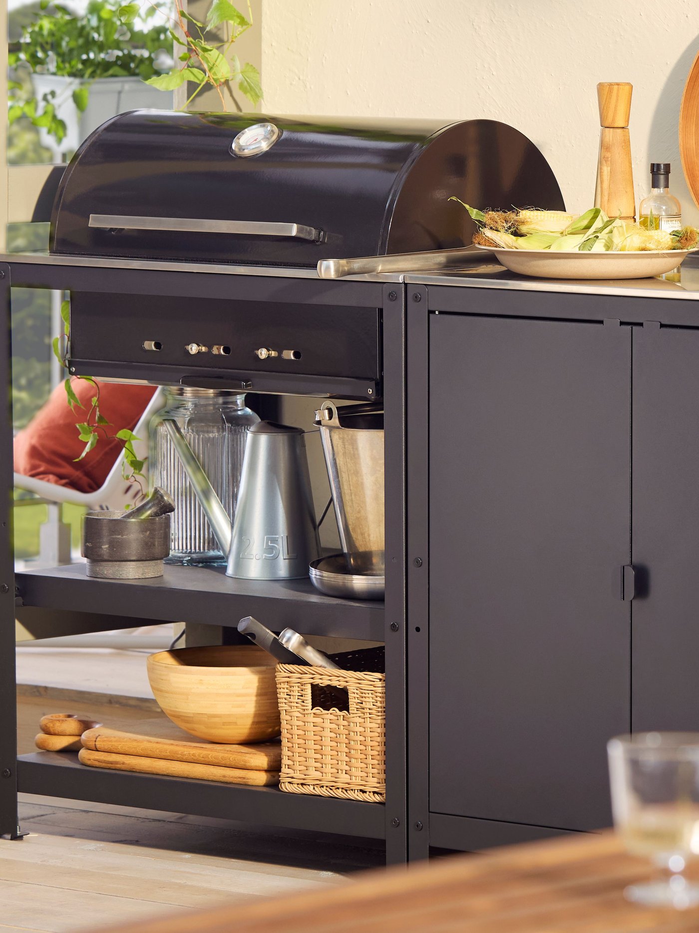 Barbecue au charbon de bois d'extérieur GRILLSKÄR et îlot de cuisine en acier inoxydable noir avec accessoires pour griller et cuisiner.