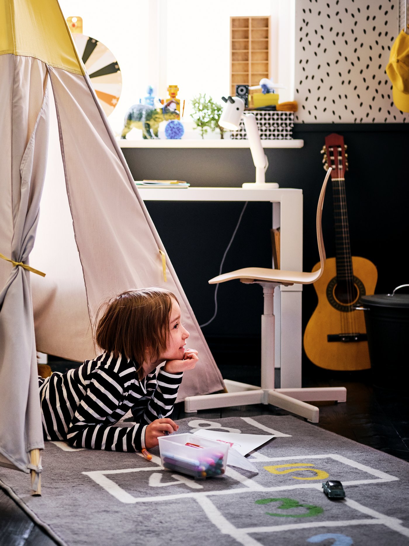 Un garçon étendu sur le ventre regarde à l’extérieur d’une tente pour enfant, les coudes appuyés sur un tapis hemmahos.