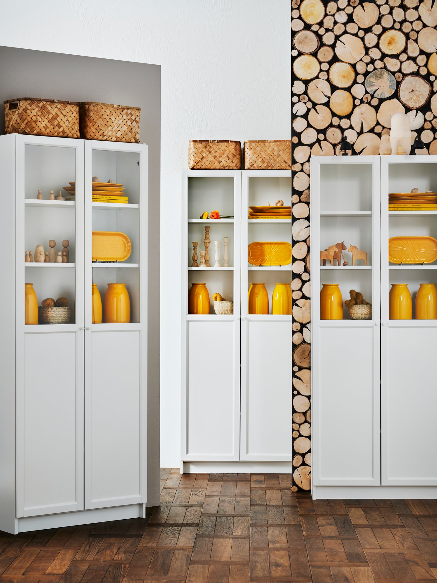 BILLY bookcases filled with KOPPARBJÖRK vases, decorative plates and other knickknacks are in different areas of a room.