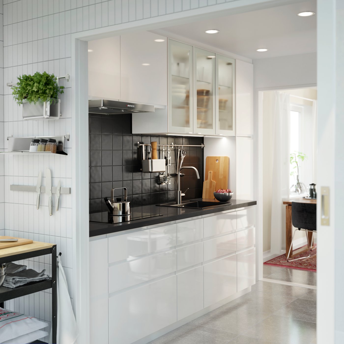 Bílá kuchyně s bílými čely zásuvek a skleněnými dvířky s vysokým leskem, pracovní deska z černého kamene.