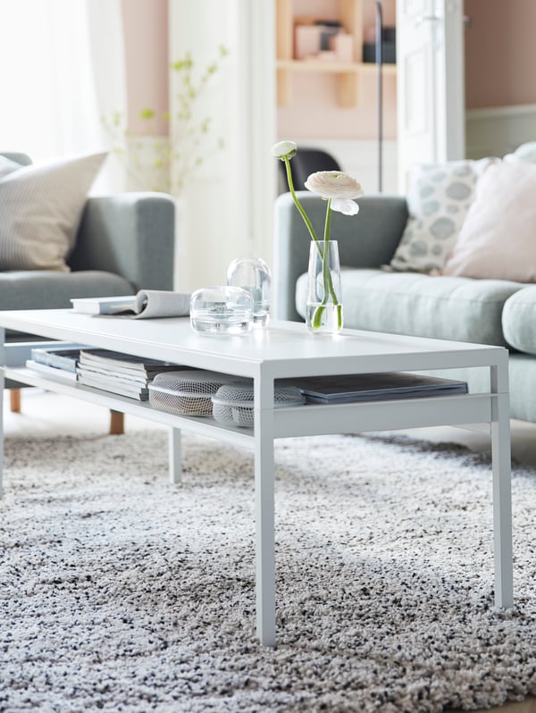 IKEA NYBODA long white coffee table with books stored underneath on a thin, slim shelf.