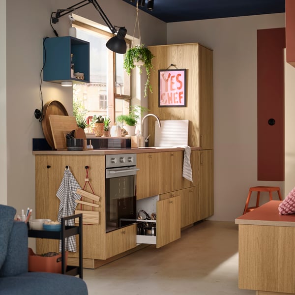 A small kitchen has METOD cabinets with SINARP fronts in oak veneer, an oven, a sink and an integrated fridge/freezer.