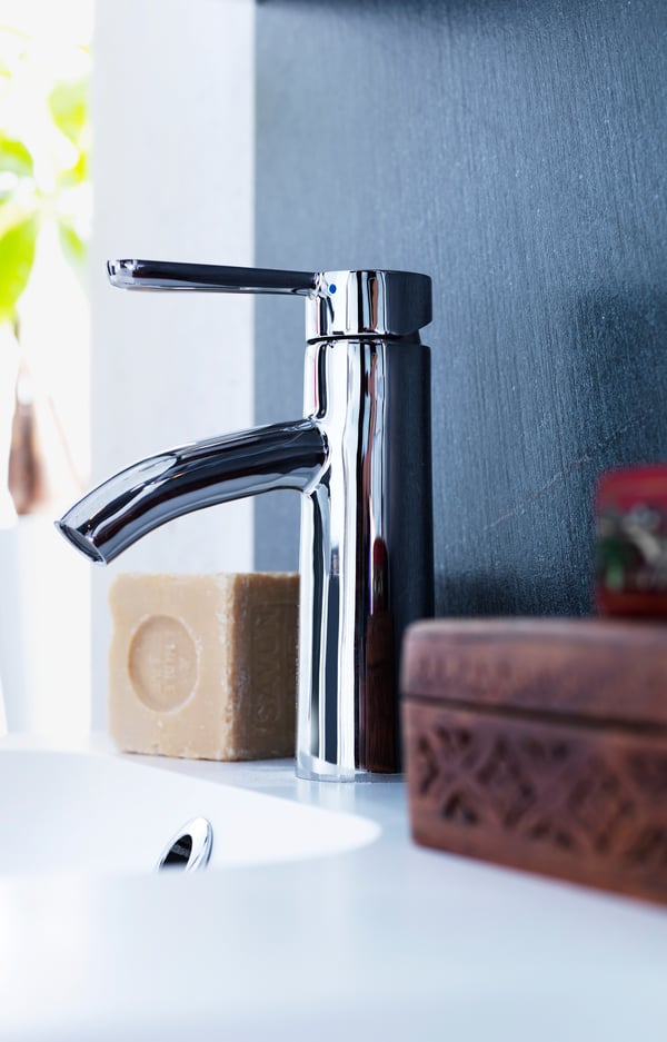 DALSKÄR wash-basin mixer tap in chrome finish with a soap bar and bathroom accessories in the background.