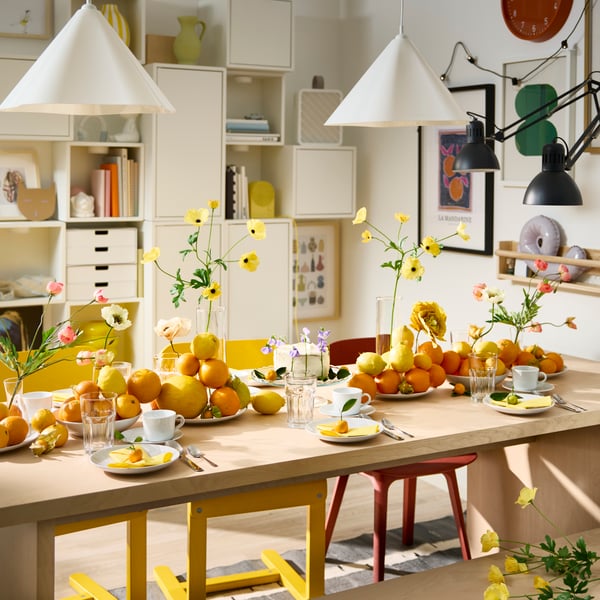 A festive table setting with white plates, POKAL glasses and decorative oranges and lemons on plates on a BERGSHYTTAN table.