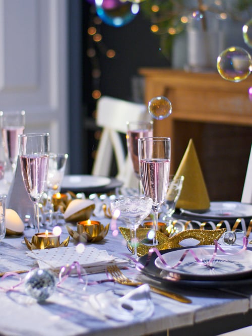 Dining room featuring multiple white champagne glasses that have slender design, placed next to multiple side plates.