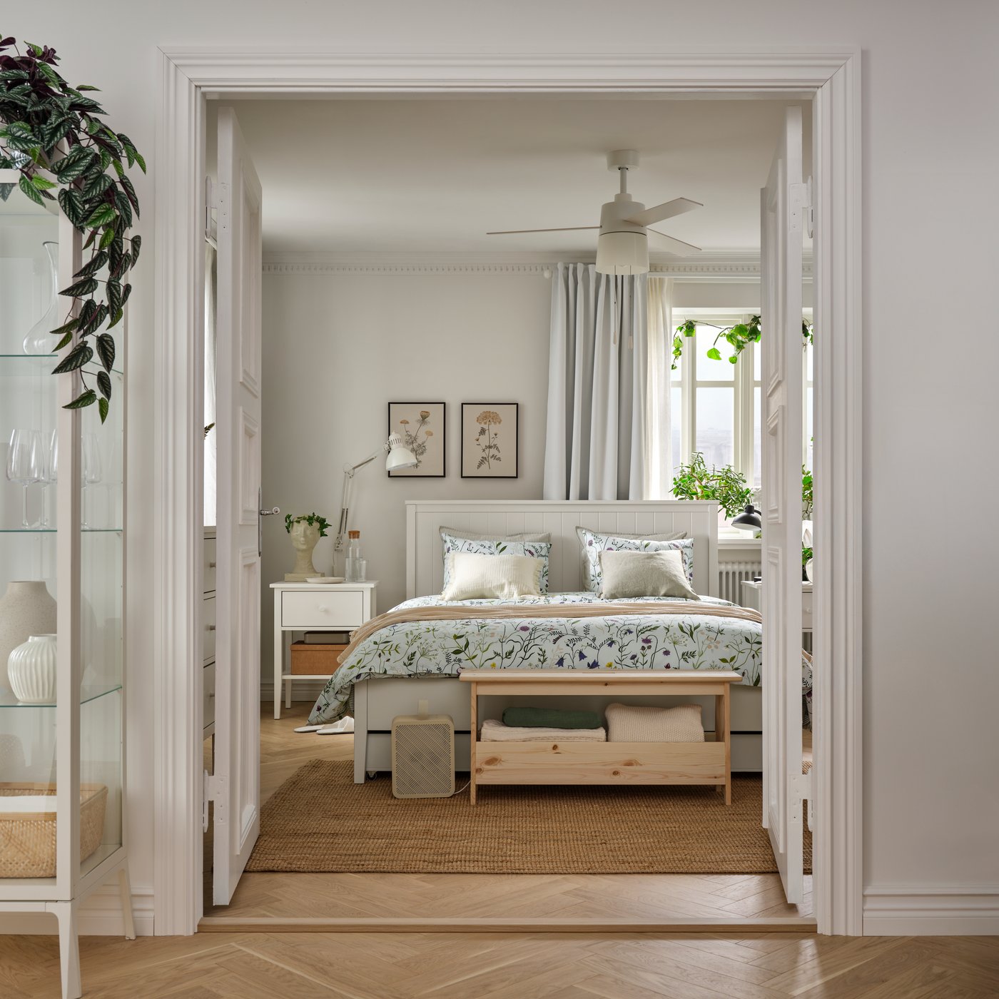 Une chambre avec un cadre de lit GULLABERG blanc doté de quatre coffres de rangement, agrémentée d'un purificateur d'air UPPÅTVIND et de plantes.