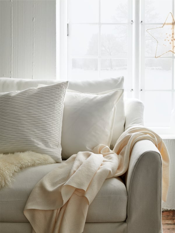 FARLOV sofa in the living room in white with two white VANDEROT and GURLI cushions on top together with an INGRUN throw. 
