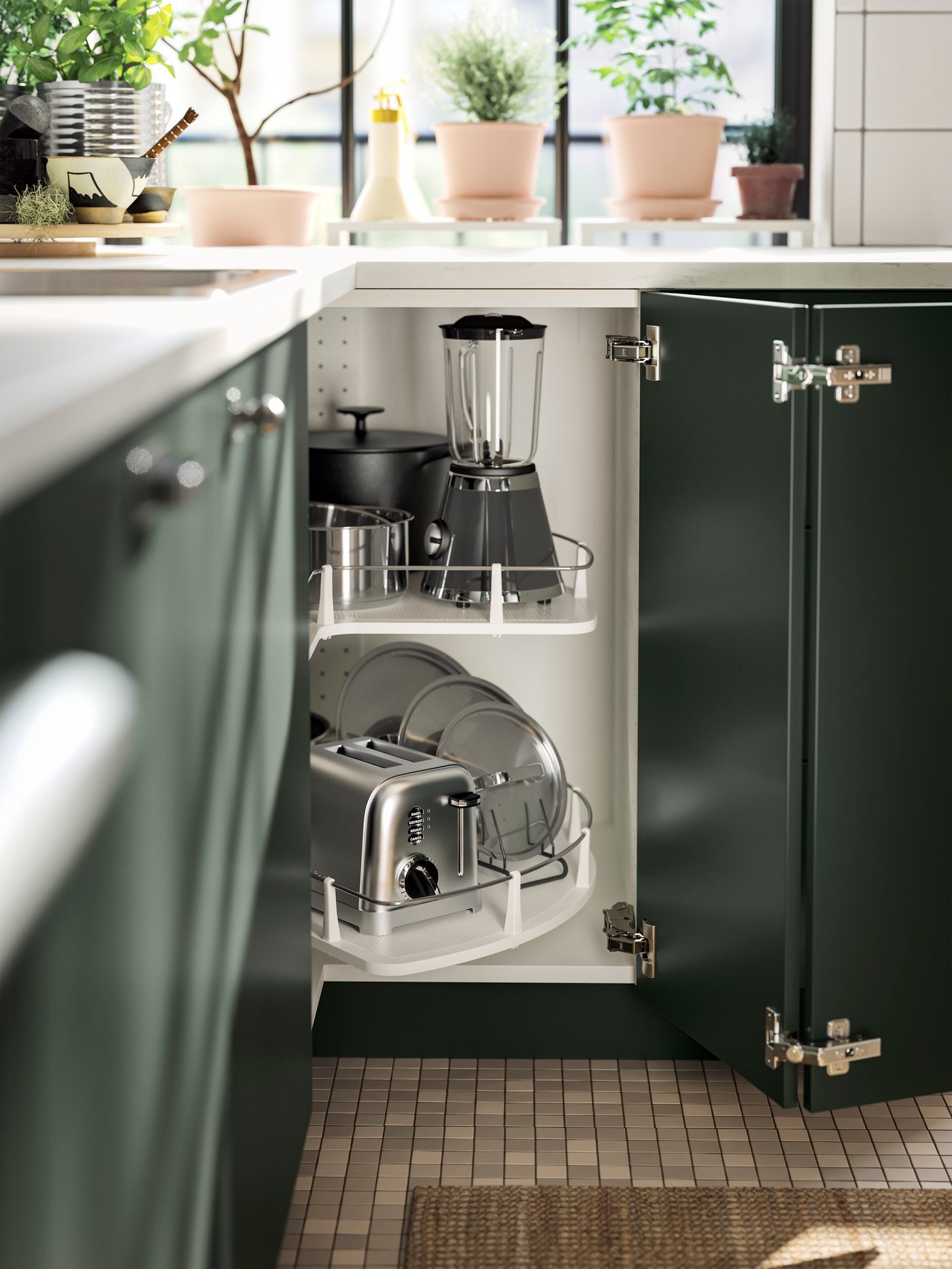 An open corner cabinet in a kitchen with deep green HAVSTORP kitchen fronts and an inner carousel, with various pots and pans.