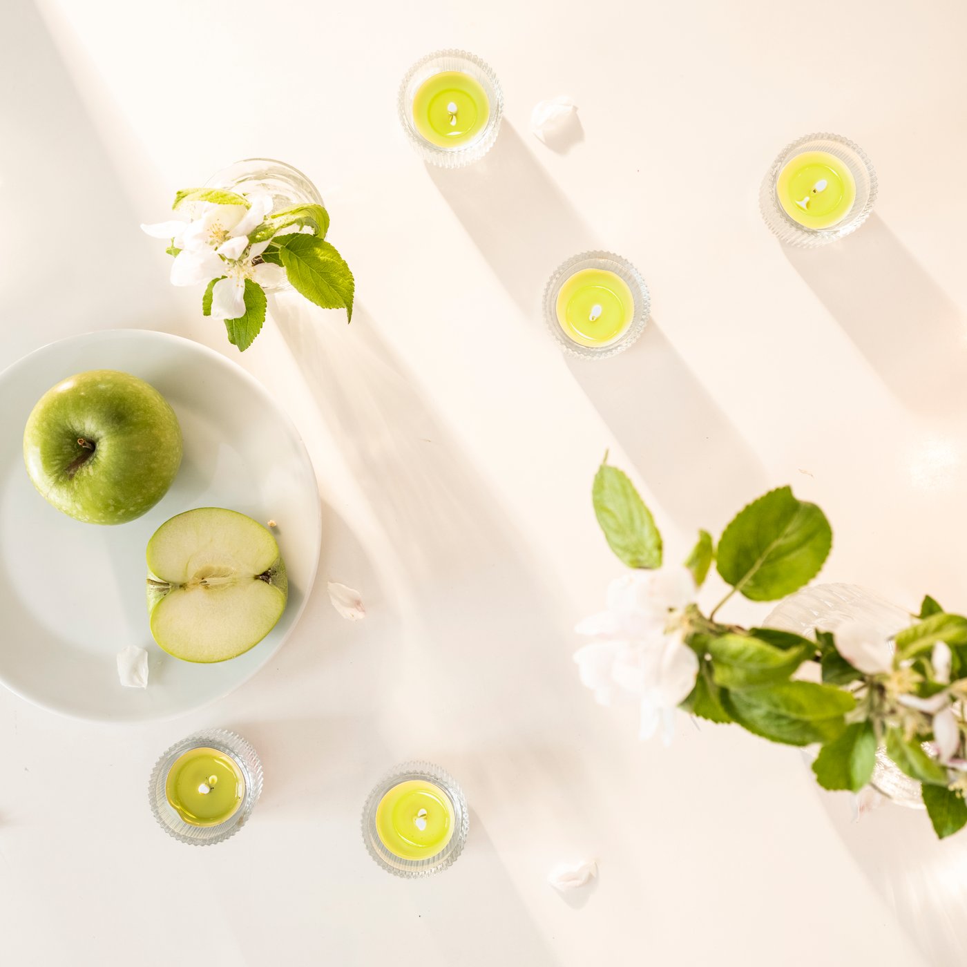 Una vela aromática LÖVSKOGSLUND con aroma a manzana, en tono verde claro.