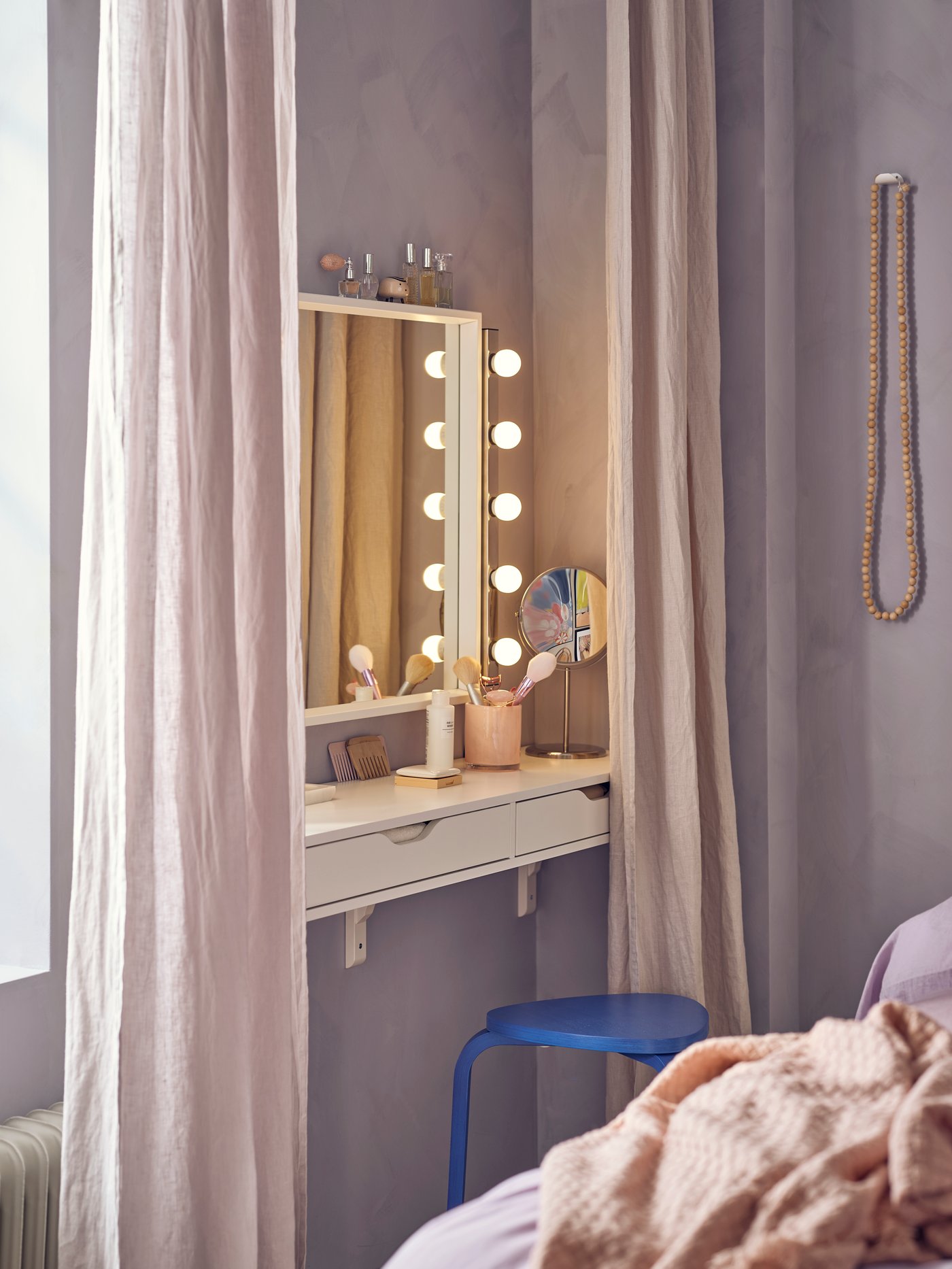 Rincón del dormitorio: estante EKBY ALEX con cajones montado bajo un espejo NISSEDAL, iluminado con lámparas de pared y rodeado de cortinas.