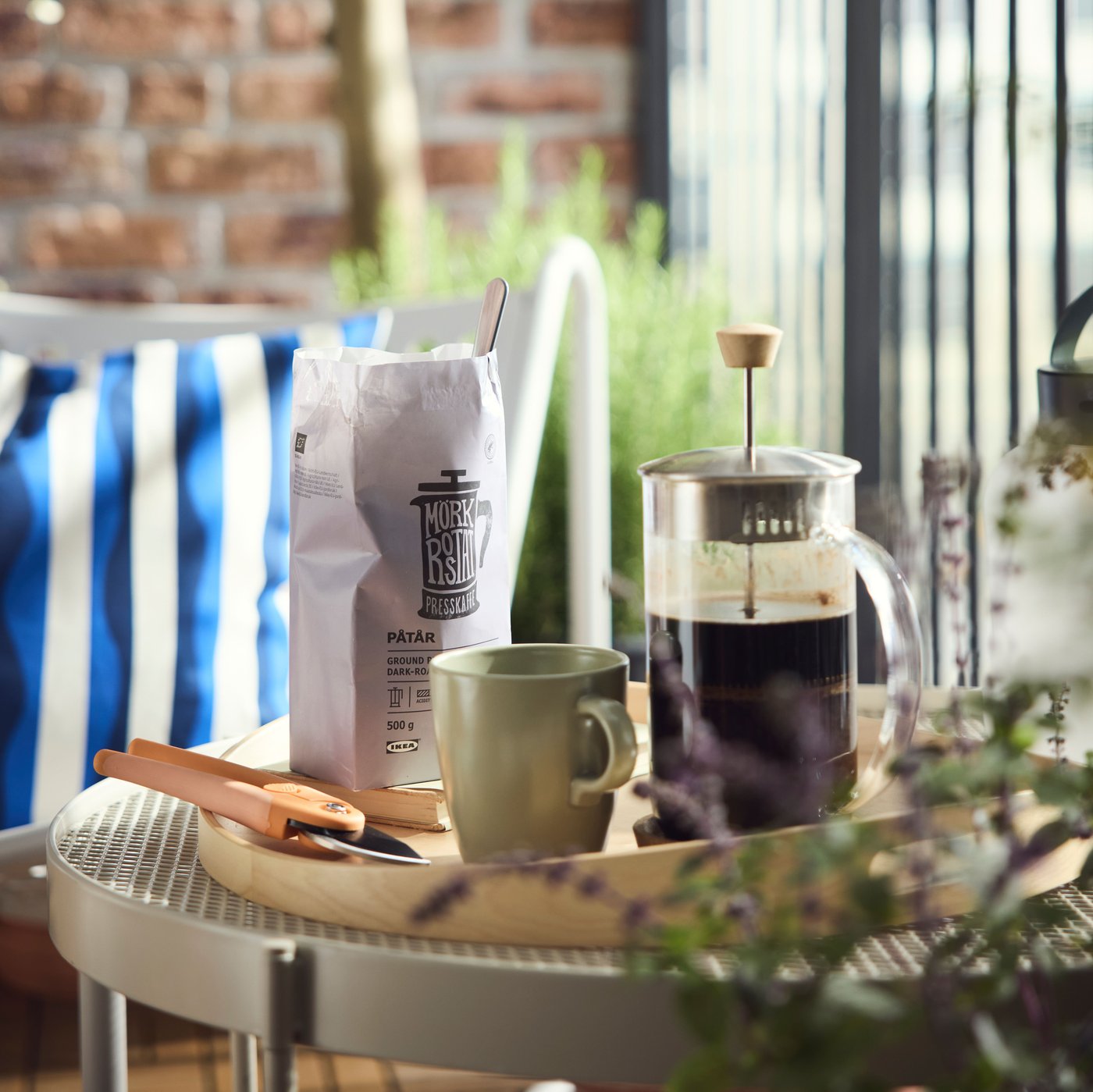 Un confezione di caffè, una tazza e caffettiera pressofiltro su un vassoio.