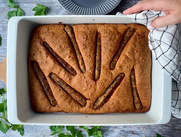 Gros plan sur le « Toad in the Hole » végétalien dans un plat à four blanc.