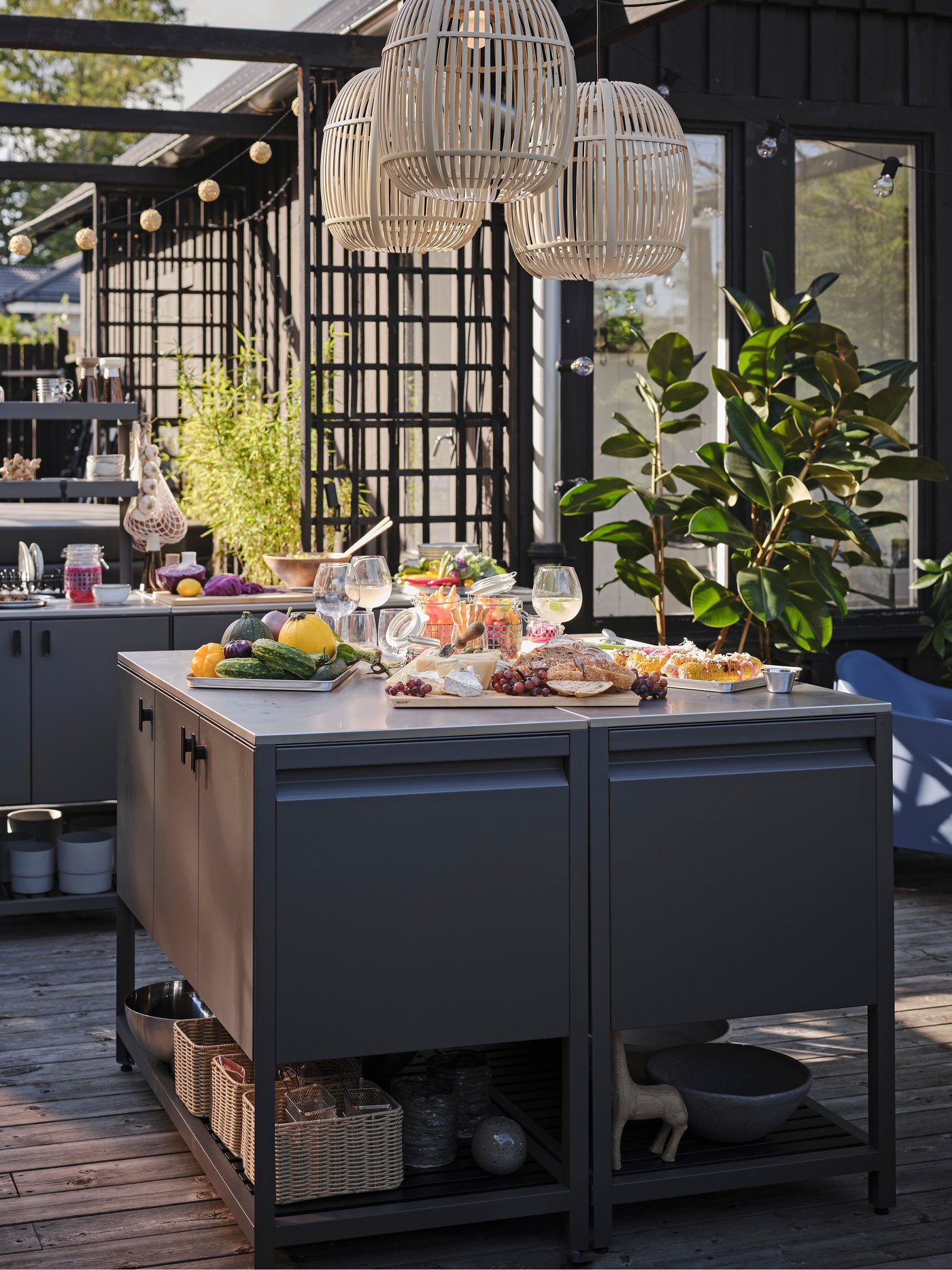 A large patio at sunset with a summer buffet on two BÅTSKÄR closed kitchen units combined into a larger work surface.