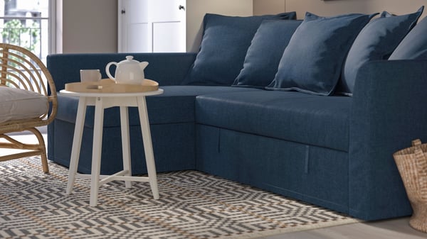 Mörkblå HOLMSUND bäddsoffa med schäslong placerad i ett luftigt vardagsrum.