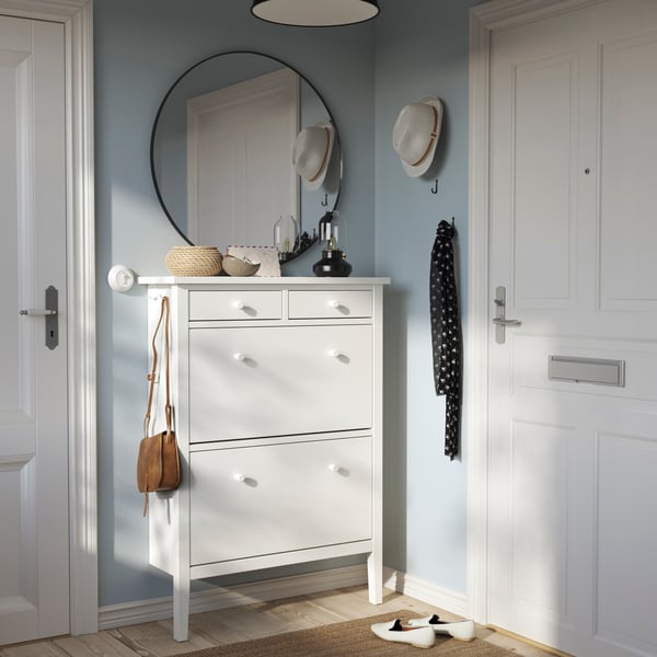 Un zapatero blanco GULLABERG en el recibidor de un hogar con decoracines y un espejo en la pared.