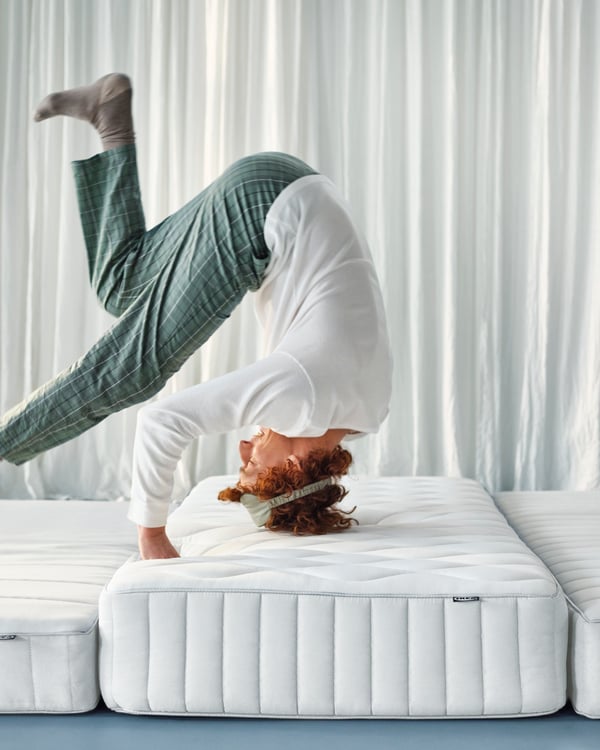 A man rolling onto a mattress in his pajamas.