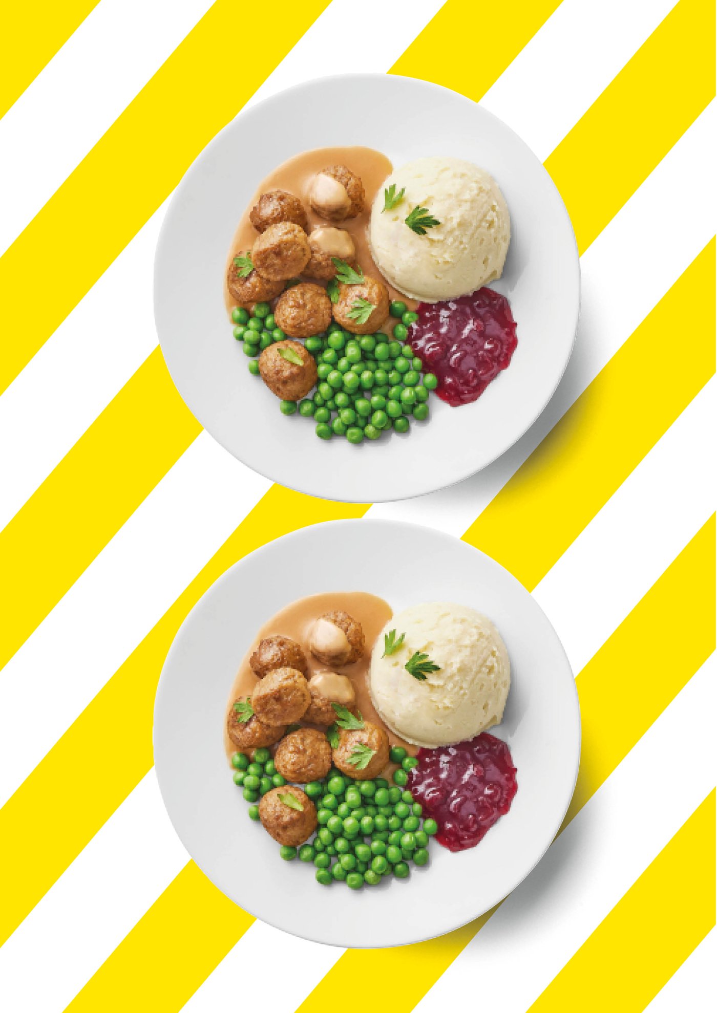 Zwei identische weiße Teller mit Fleischbällchen, Kartoffelpüree, Erbsen, Preiselbeeren und brauner Sauce sind auf einem Hintergrund mit gelb-weißen Diagonalstreifen angeordnet.