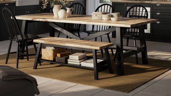 Een zwarte SKOGSTA eetkamerbank met opbergruimte naast een SKOGSTA eettafel in de keuken.