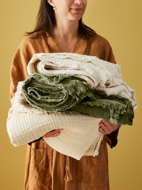 A person holding white VALLKRASSING throws and a grey-green throw.