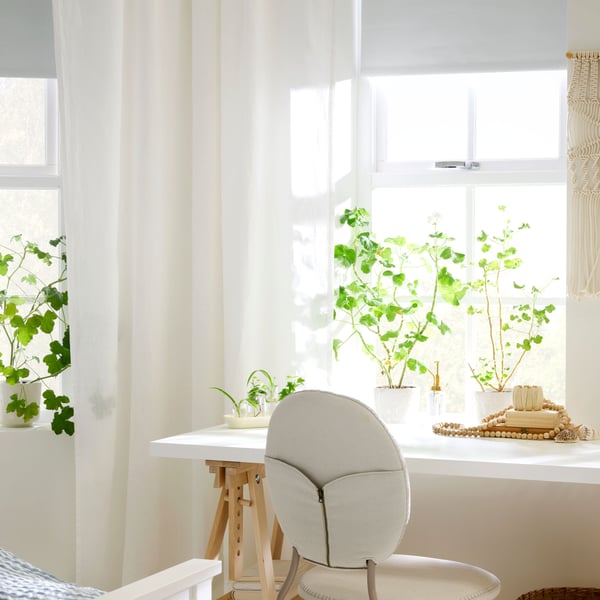 A bright workspace with a white LAGKAPTEN desk in front of a window with sheer curtains. A BJÖRKBERGET chair is by the desk.