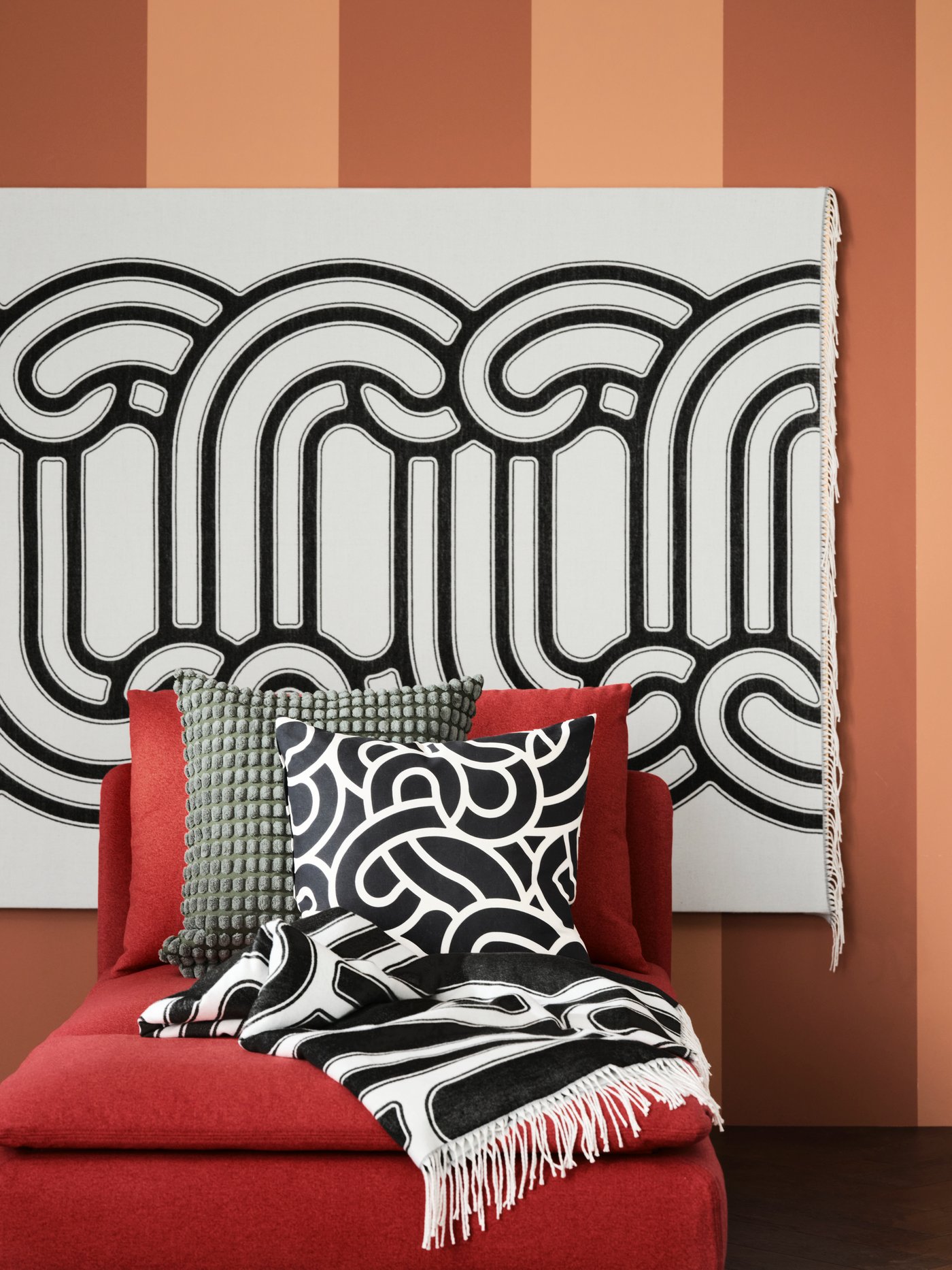 ESSEBODA footstool in anthracite with a pile of cushions in different colours like olive-green, grey-green and light beige.