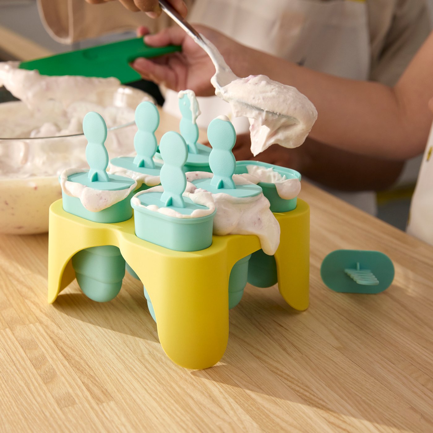 A close-up of yellow and green UPPFYLLD ice lolly makers being filled with yoghurt to become popsicles.