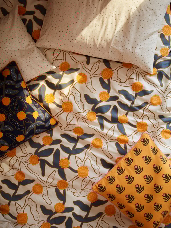 A colorful flower patterned bed linen with pillows.