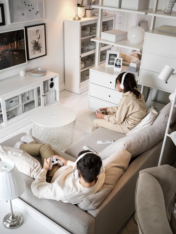 Twee tieners spelen een videospel terwijl ze op de bank zitten.