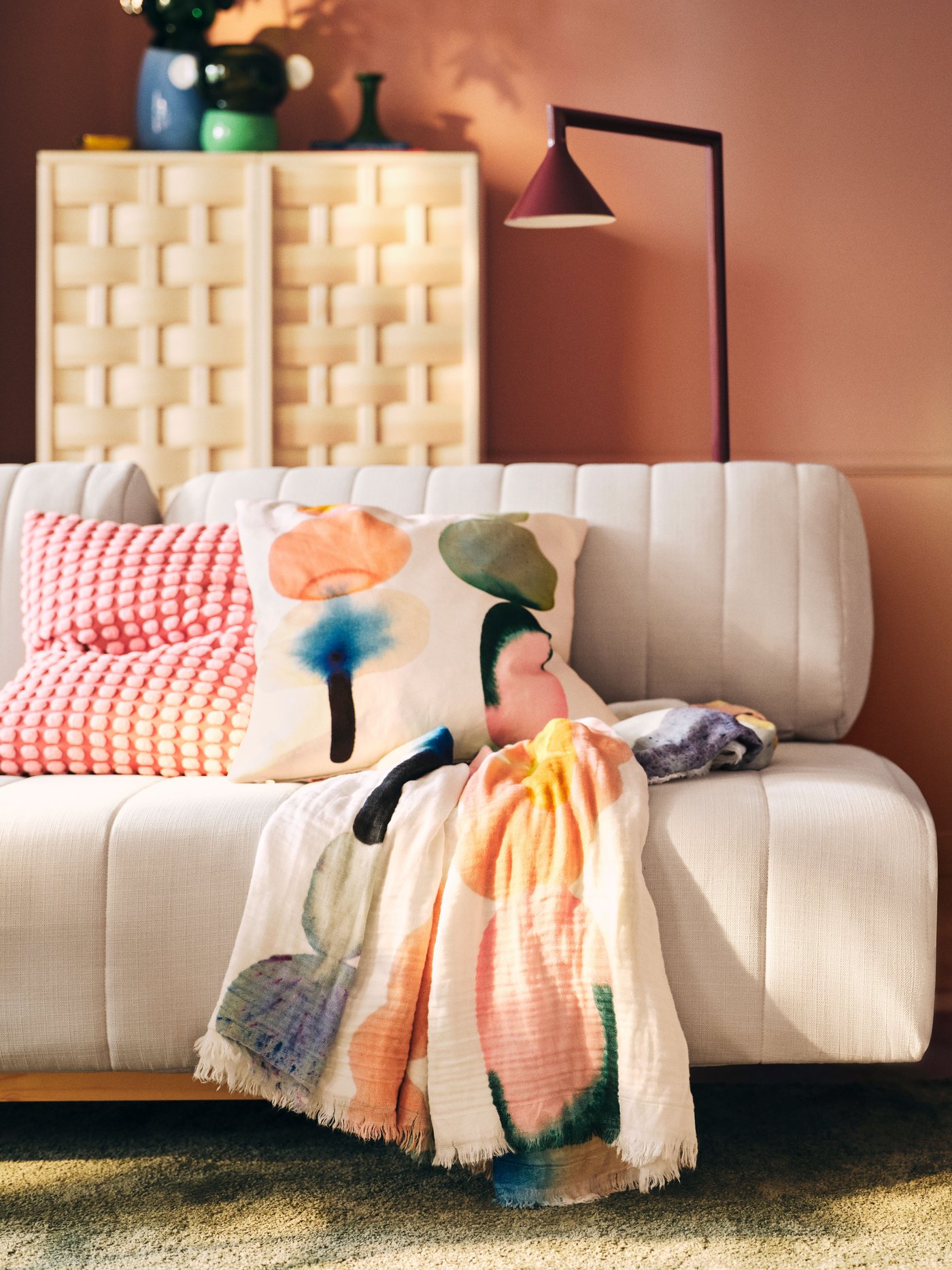Verschiedene Artikel der aktuellen IKEA PS 2026 Kollektion - unter anderem ein beiges Sofa, eine bunt gemusterte Decke, eine dunkelrote IKEA PS 2026 Leseleuchte und ein IKEA PS 2026 Schrank aus Kiefer