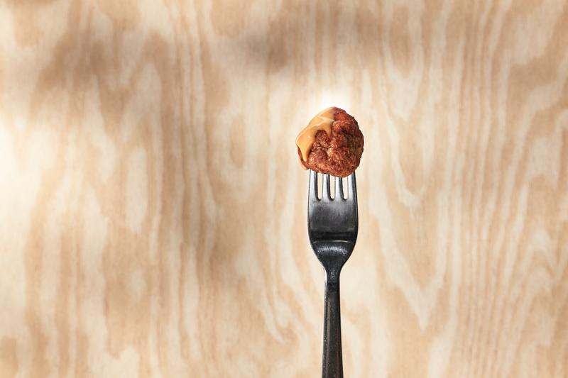 Une fourchette avec une boulette de viande sur fond en bois.