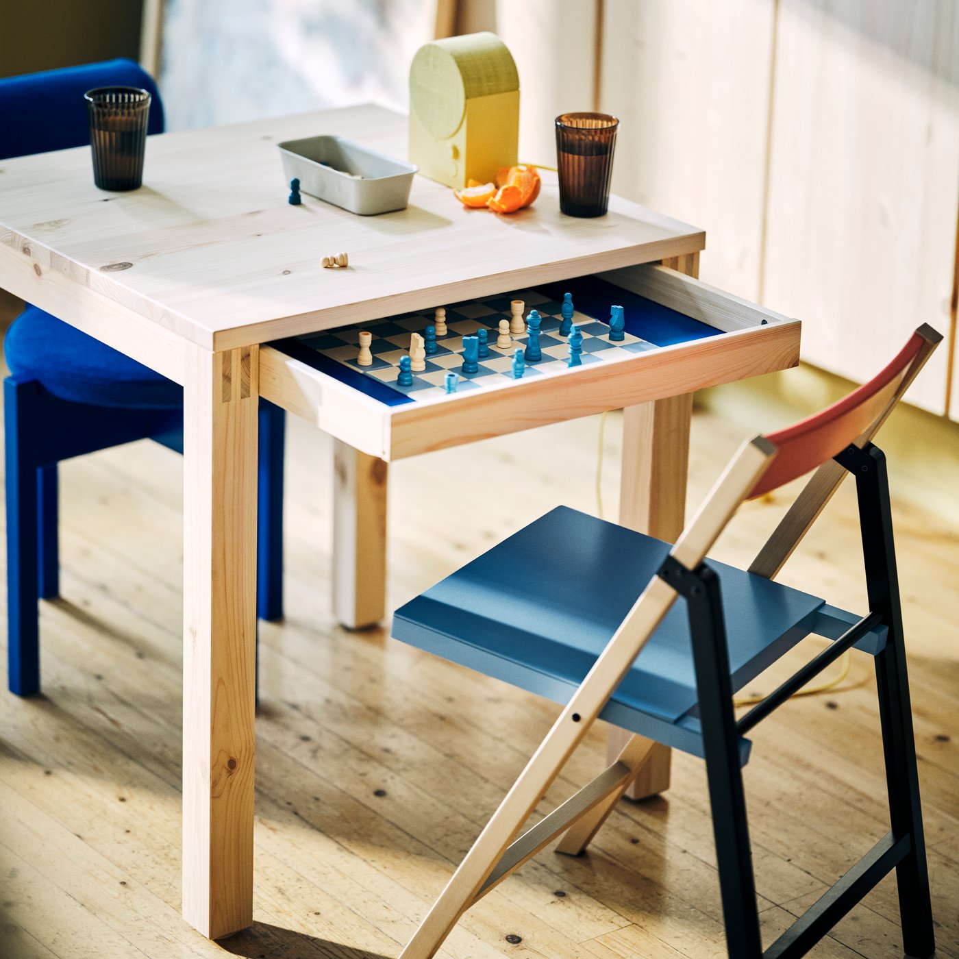 An IKEA PS 2026 table with drawer and folding chair in a small flat.