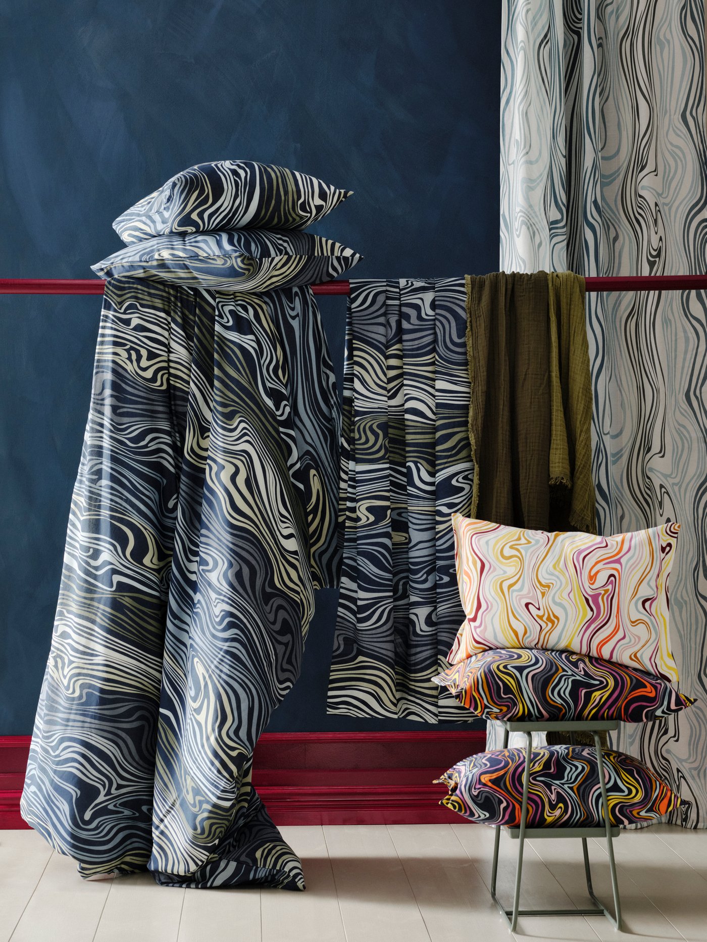 Langsir KLIPPNEJILKA tergantung di belakang palang yang mempunyai kelengkapan tidur KLIPPNEJLIKA padanya. Sarung kusyen KLIPPNEJLKA terletak di atas meja berdekatan.