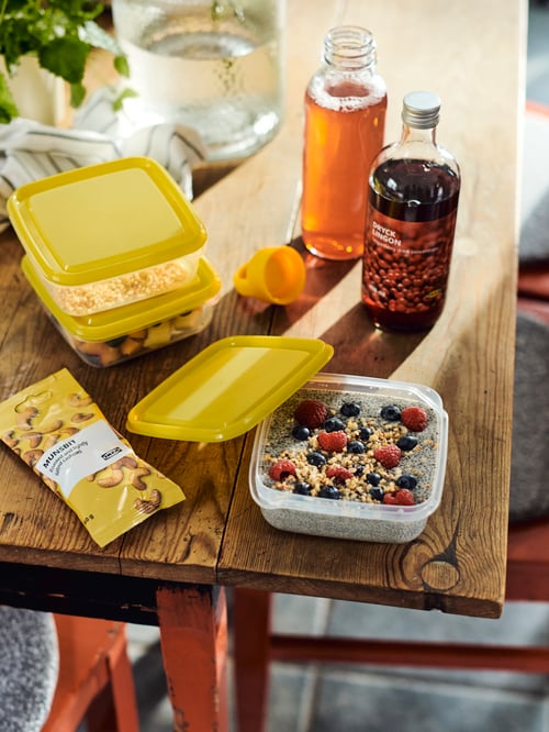 A wooden tabletop with DRYCK LINGON lingonberry syrup, PRUTA food containers and a packet of MUNSBIT roasted cashews.