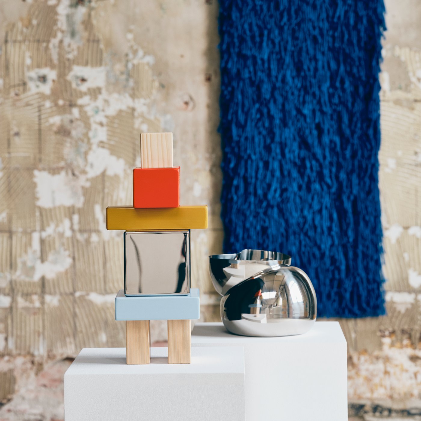Close up of three objects from IKEA KONSTRUNDA art collection. A sculpture, a bowl and a blue rug with long lashes.
