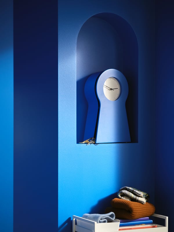 A blue wall with alcove has a IKEA PS 1995 clock inside