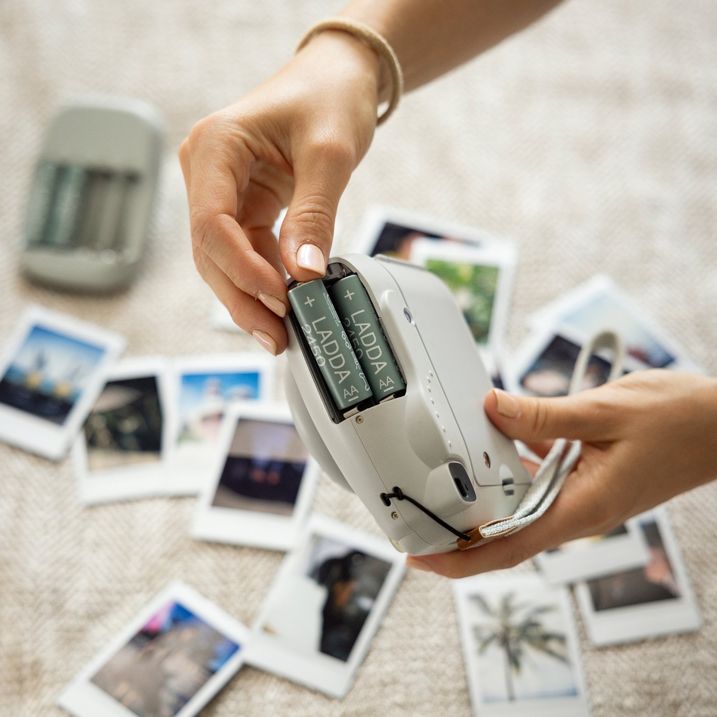 Ręka wkładająca akumulatorki LADA do aparatu typu instax