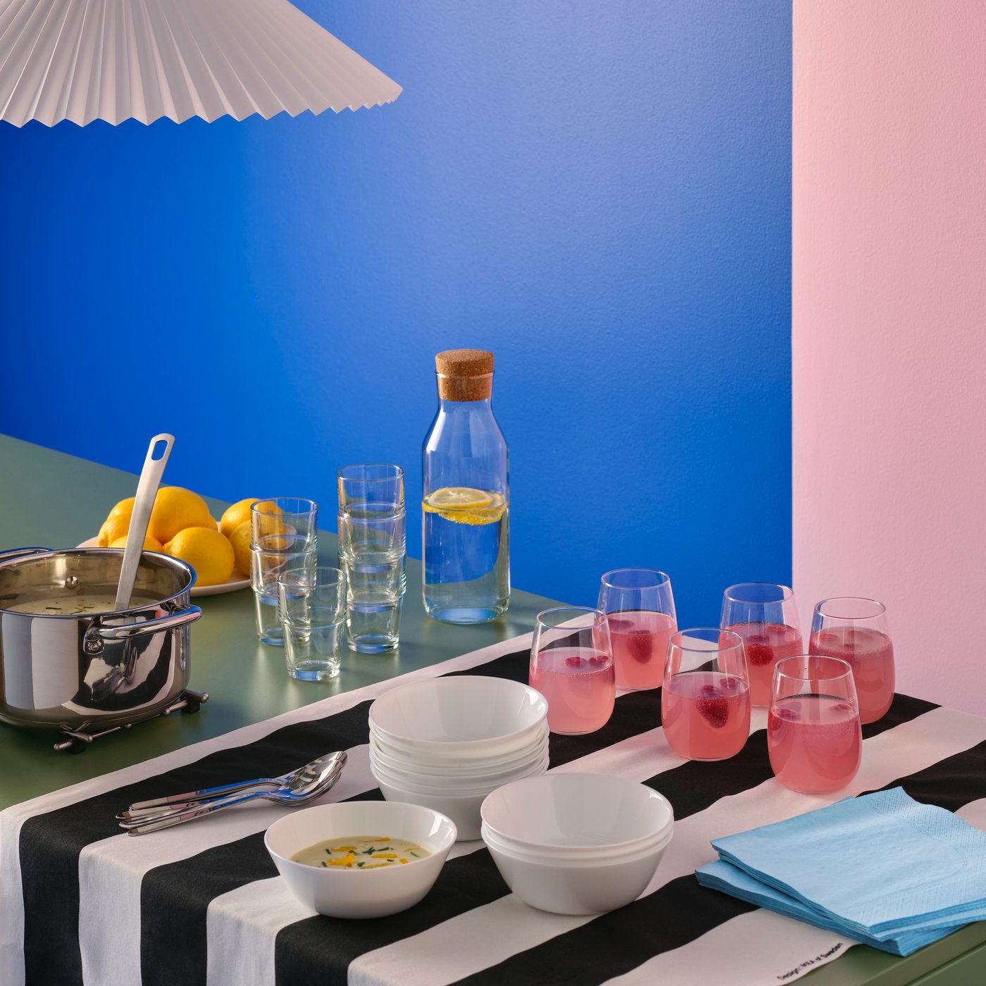 A colourful soup buffet with stacked OFTAST bowls, STORSINT glasses with pink drink, and an IKEA 365+ carafe with water.
