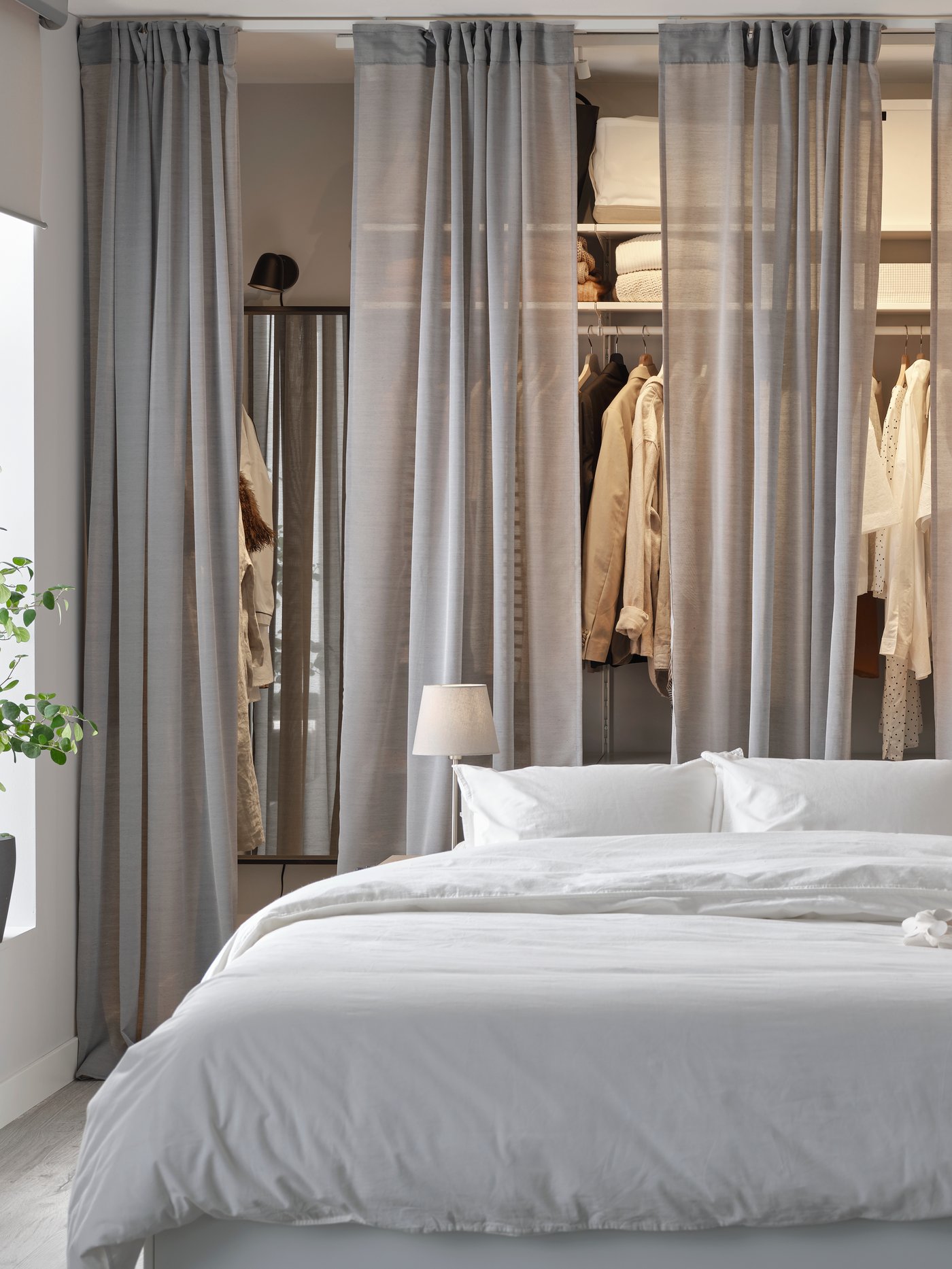 An image of a bed with wardrobes in the background lit up by some light.