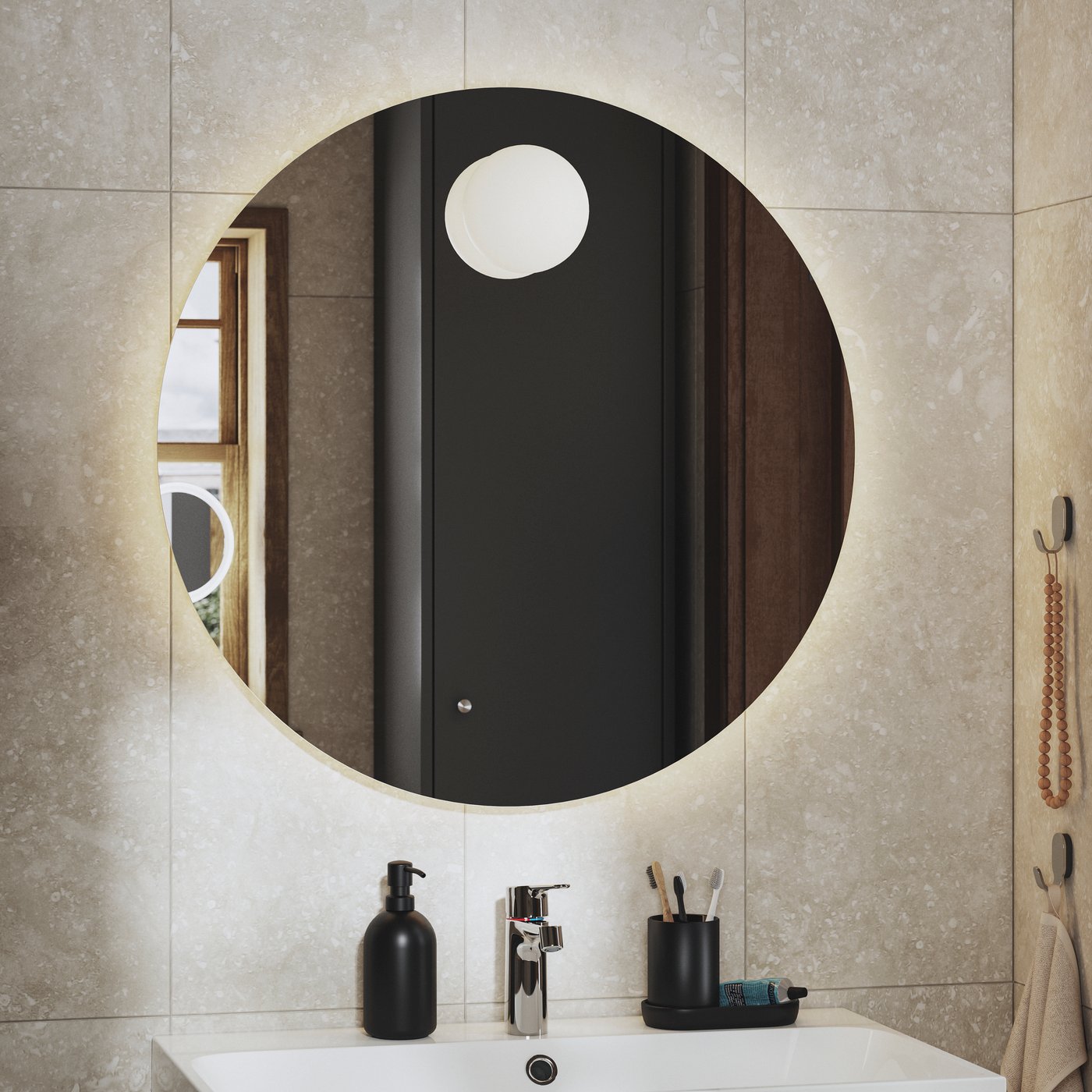 Okrągłe lustro FAXÄLVEN z wbudowanym oświetleniem zawieszone nad białą umywalką w słonecznej łazience.