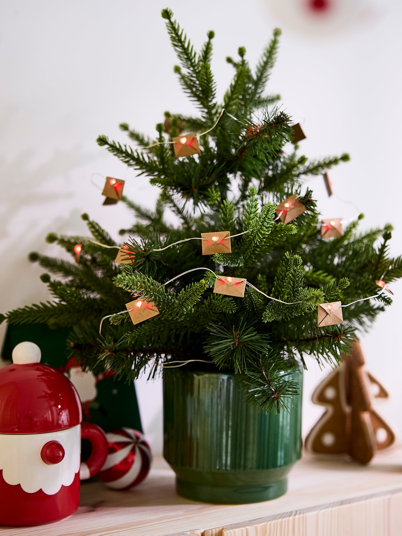 Liten julgran dekorerad med prydnader står i en ljus inomhusmiljö.