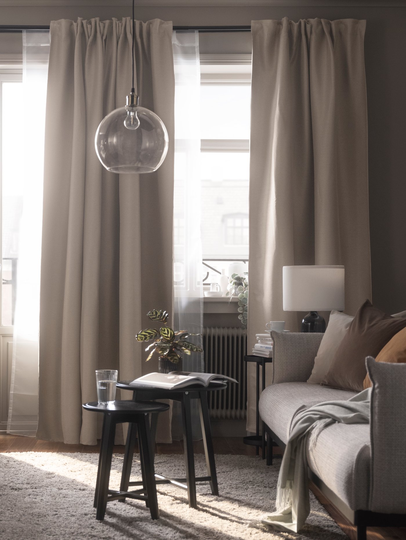 A beige VILBORG room darkening curtains, 1 pair in the living room framing the windows.