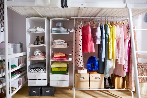 Closet con ropa de varios colores, cajas para organizar y barra de colgar ropa.