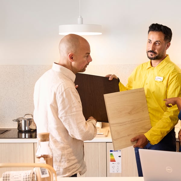 An IKEA co-worker is showing a customer material samples in a kitchen showroom.