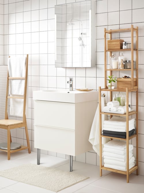 Bathroom with a shelving unit with towels and a four-piece bathroom set, a wash-stand with drawers, and a mirror cabinet.
