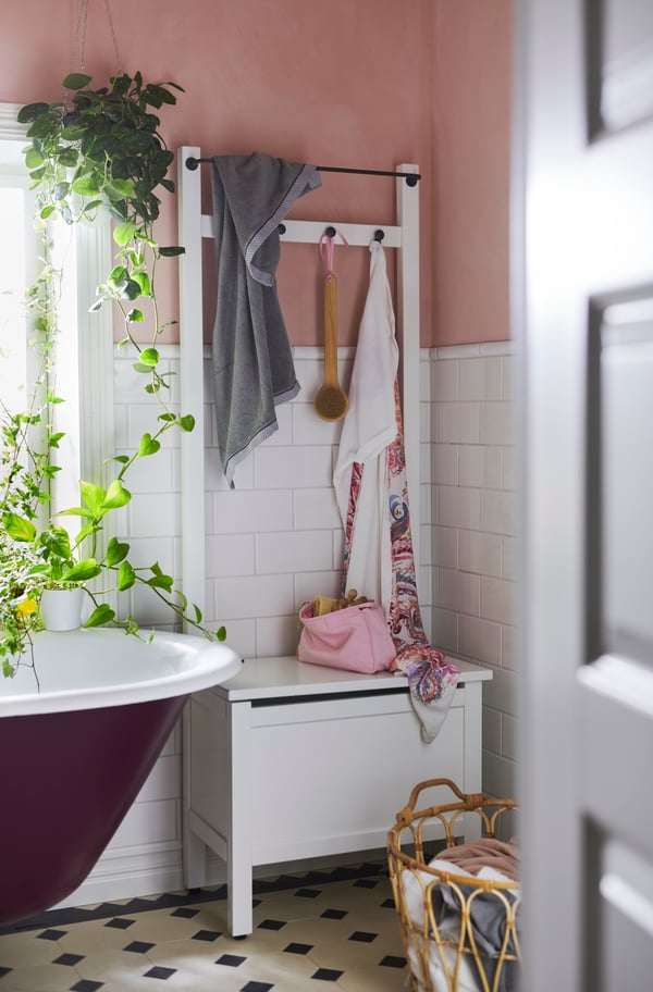Kleine weiße Truhenbank im Badezimmer mit Hakenleiste.