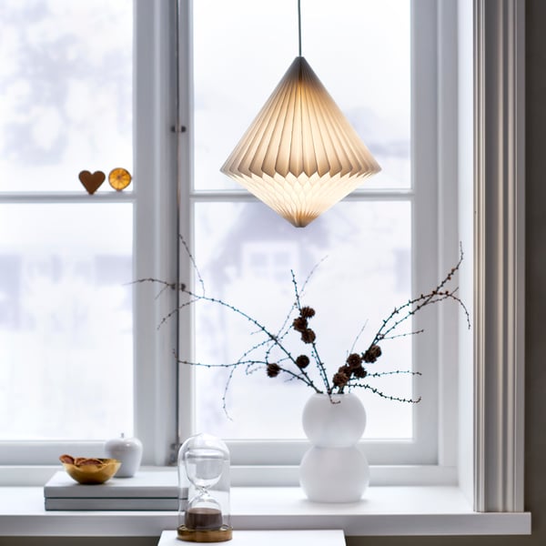 Diamantfärgad lampa i vitt papper hängande i fönster.