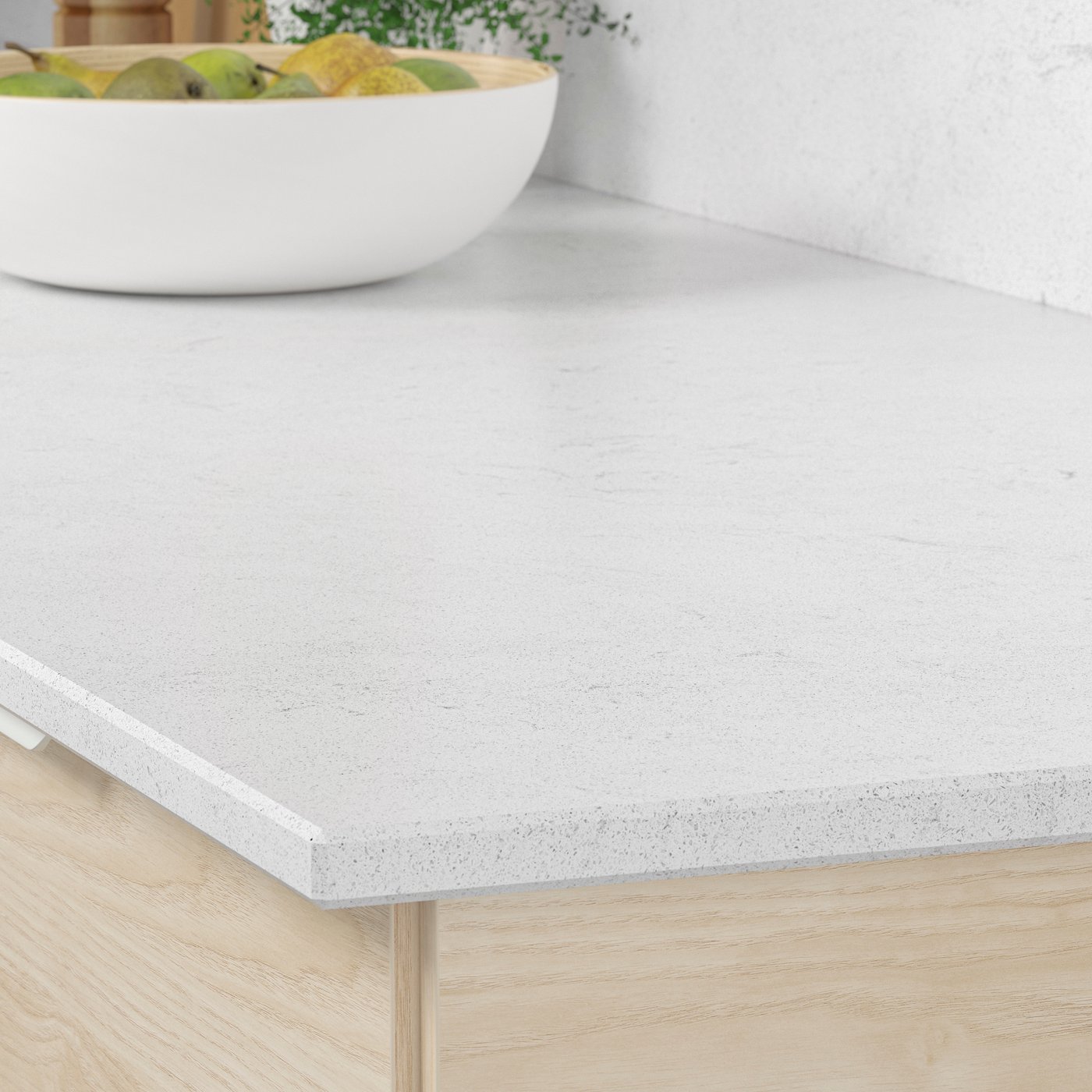 Ljus köksbänk med en skål frukt placerad ovanpå.

